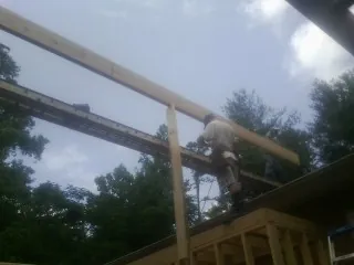 Carpenter setting a ridge beam over a new addition frame — Ice Dam Removal by Roofing Brothers in Leonard
