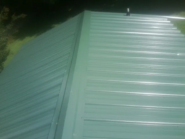 New green metal panels meeting at the ridge of a roof — Flat Roof Repair work by our crew in Leonard