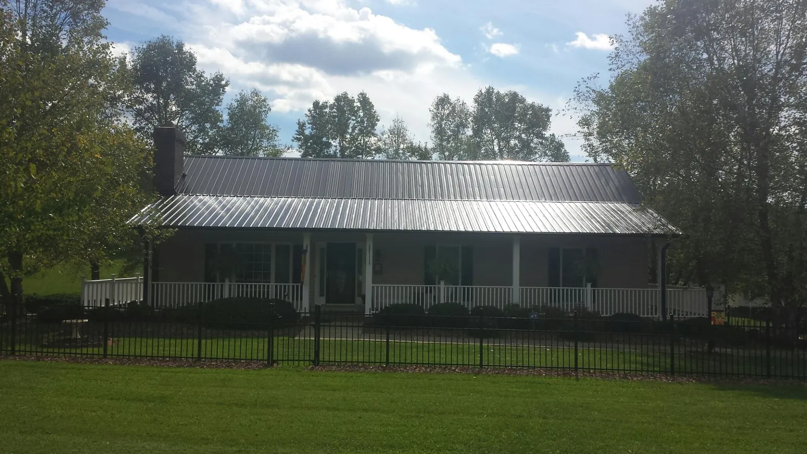 Gray metal roof on a brick ranch with a full width front porch — Gutter Guard Installation work by our crew in Leonard